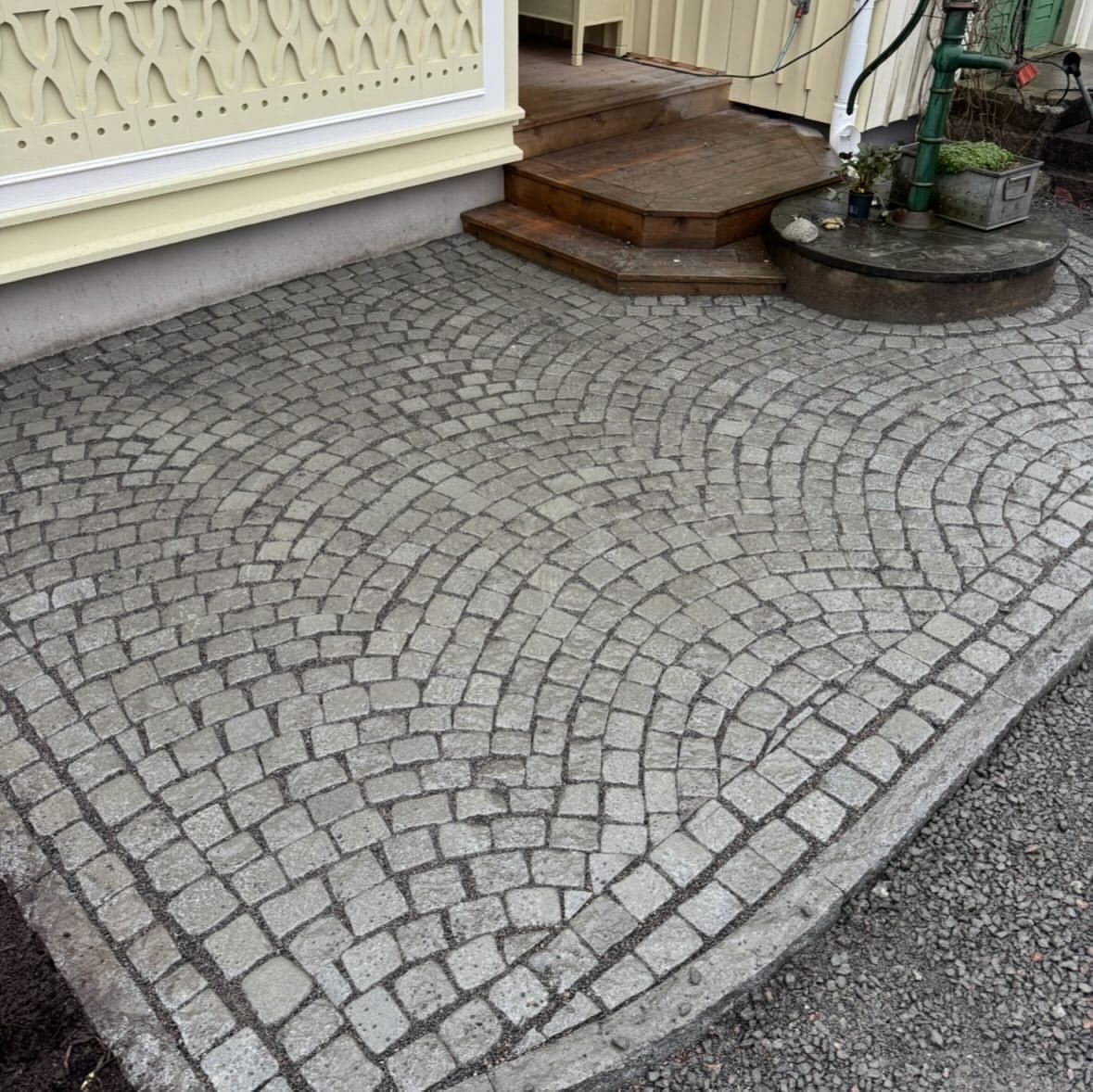 Närbild på smågatsten lagd i radie vid entrétrappan