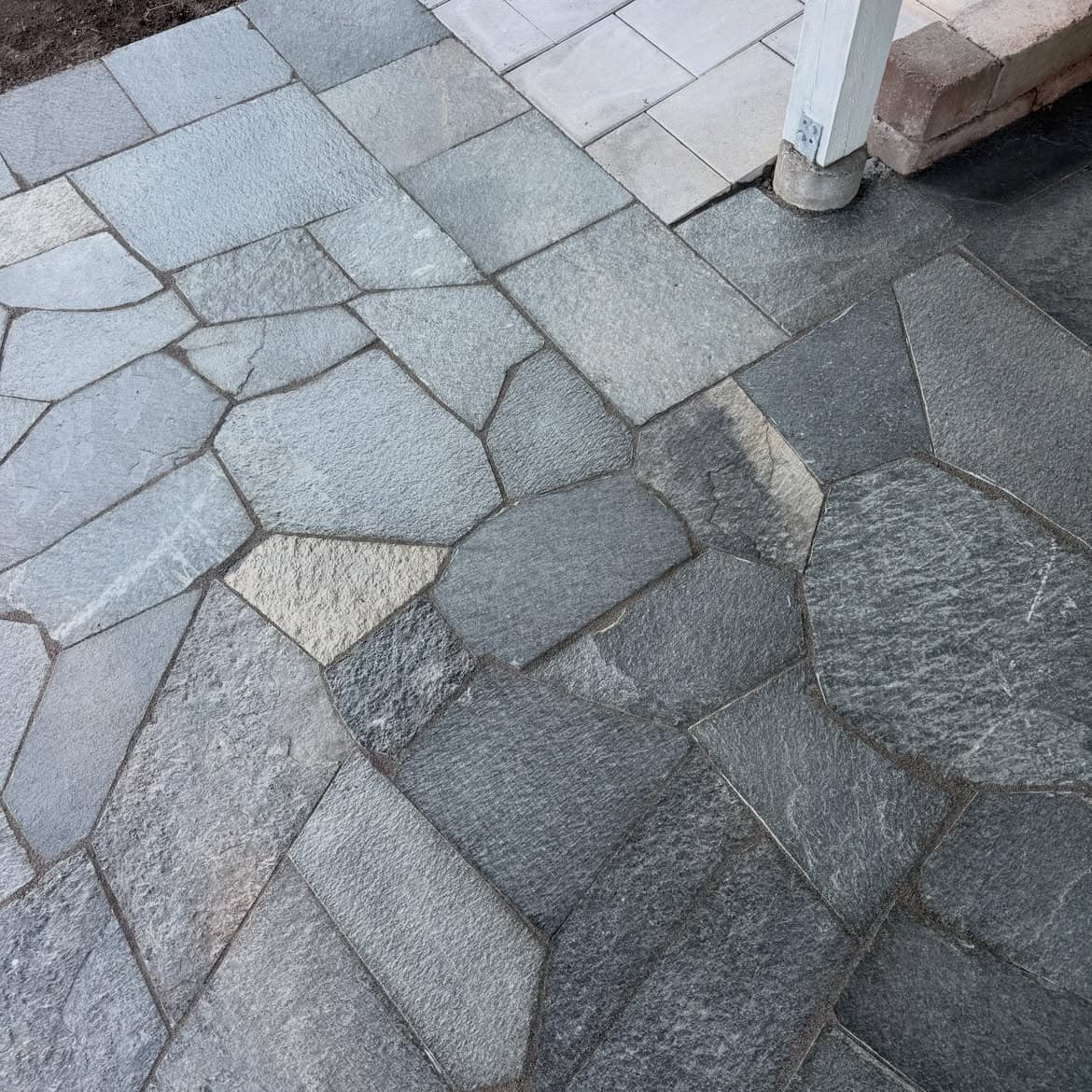 Detalj där den oregelbundna skiffern möter betongplattorna
